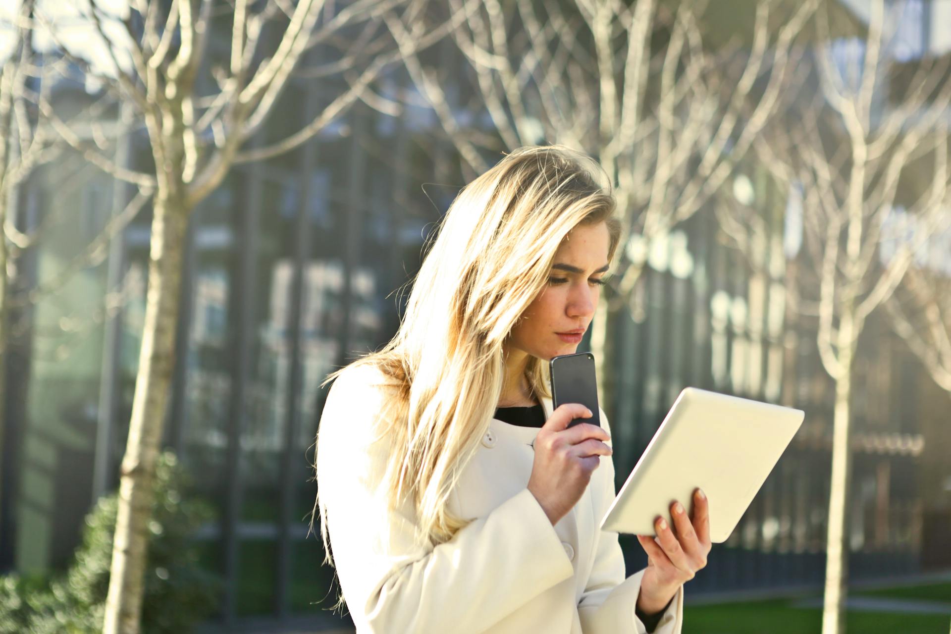 Woman looking at a tablet computer deep in thought in an outdoor setting.