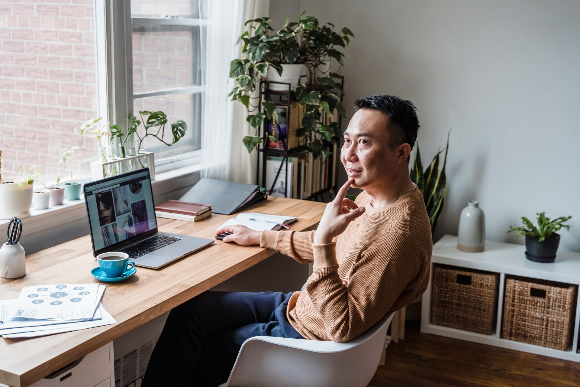 Man considering a decision while seated at a laptop.